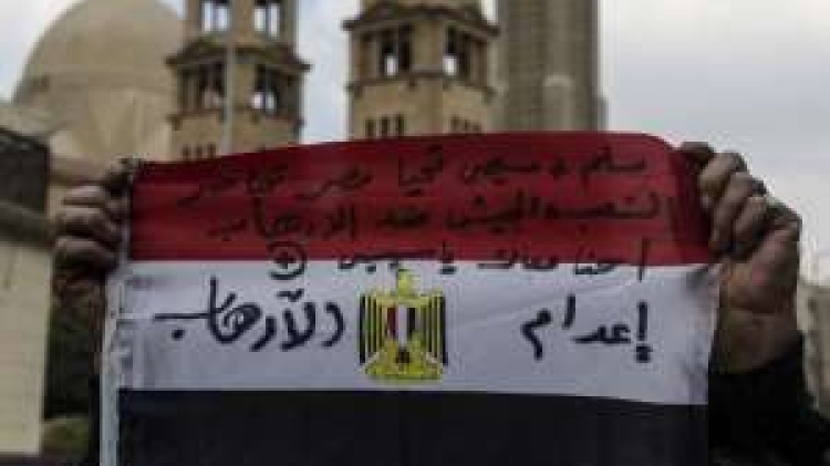 An Egyptian shows a national flag reading words in support of Egyptian President Abdel Fattah al-Sisi, the national unity and against terrorism on February 16, 2015, outside Saint-Mark's Coptic Cathedral in Cairo